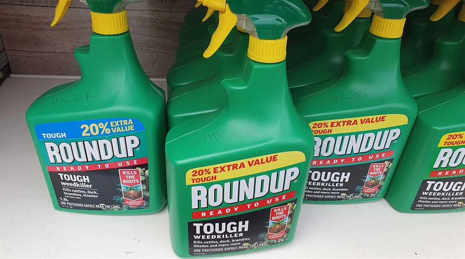 Roundup with word 'cancer' written on bottles in garden centre 
